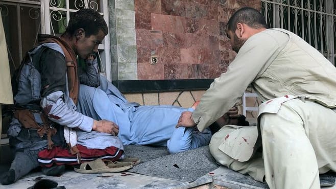 Ein verletzter Mann liegt nach einer Bombenexplosion in Mazar-e-Sharif auf dem Boden: Eine Bombe explodierte am Samstag in Afghanistan während einer Preisverleihung für Journalisten. Ein verletzter Mann liegt nach einer Bombenexplosion in Mazar-e-Sharif auf dem Boden: Eine Bombe explodierte am Samstag in Afghanistan während einer Preisverleihung für Journalisten.
