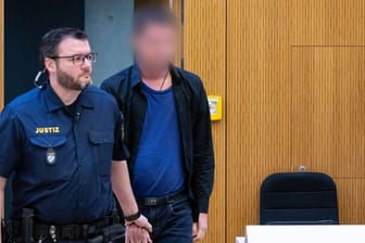06.03.2023, Bayern, München: Einer von zwei wegen Mordes angeklagten Männern (r) wird vor Beginn der Verhandlung in den Hochsicherheitsgerichtssaal vom Landgericht München II geführt.