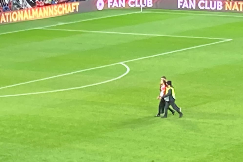 Ordner führen den Flitzer beim Länderspiel ab.