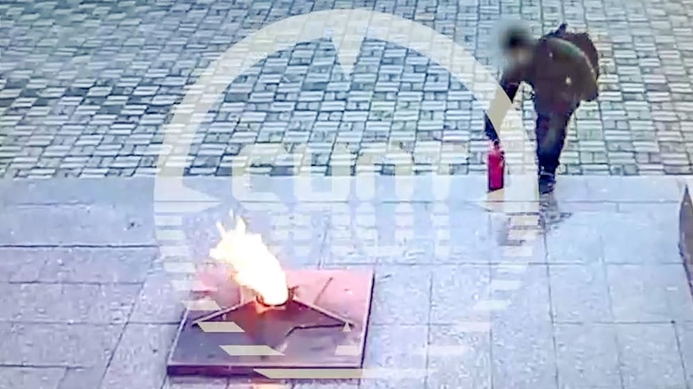 Ein Junge platziert einen Feuerlöscher in einer "Ewigen Flamme"