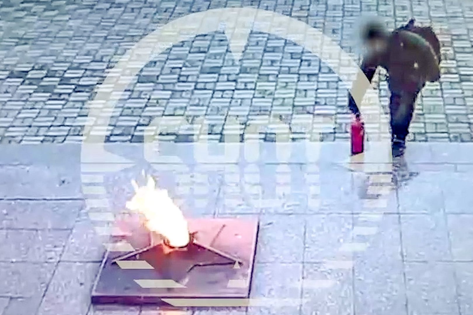 Ein Junge platziert einen Feuerlöscher in einer "Ewigen Flamme"