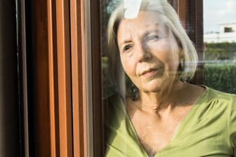 Eine Rentnerin schaut aus dem Fenster (Symbolbild): Ein Erbe ist grundsätzlich erbschaftsteuerpflichtig. Doch es gibt Freibeträge.