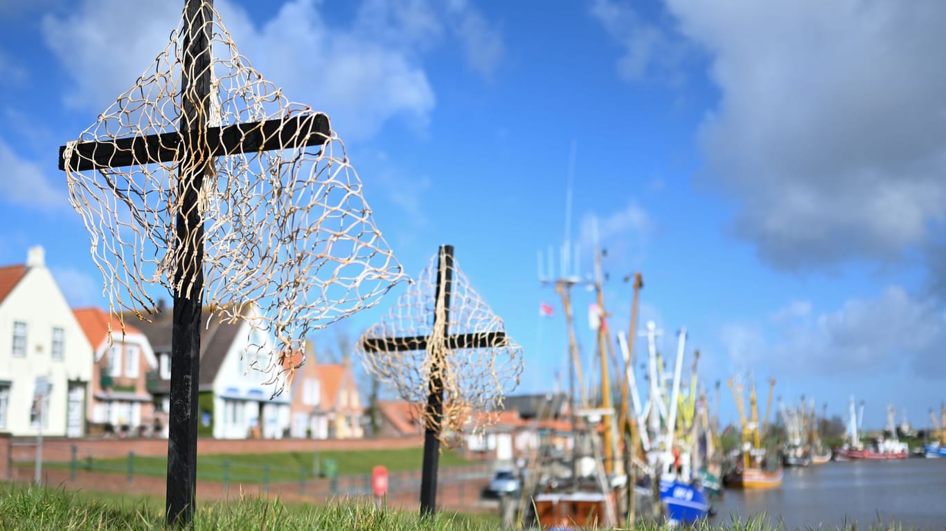 Schwarze Kreuze mit Netzen stehen als stiller Protest der Fischer an einem Hafen: Nordseefischer fürchten um ihre Existenz.