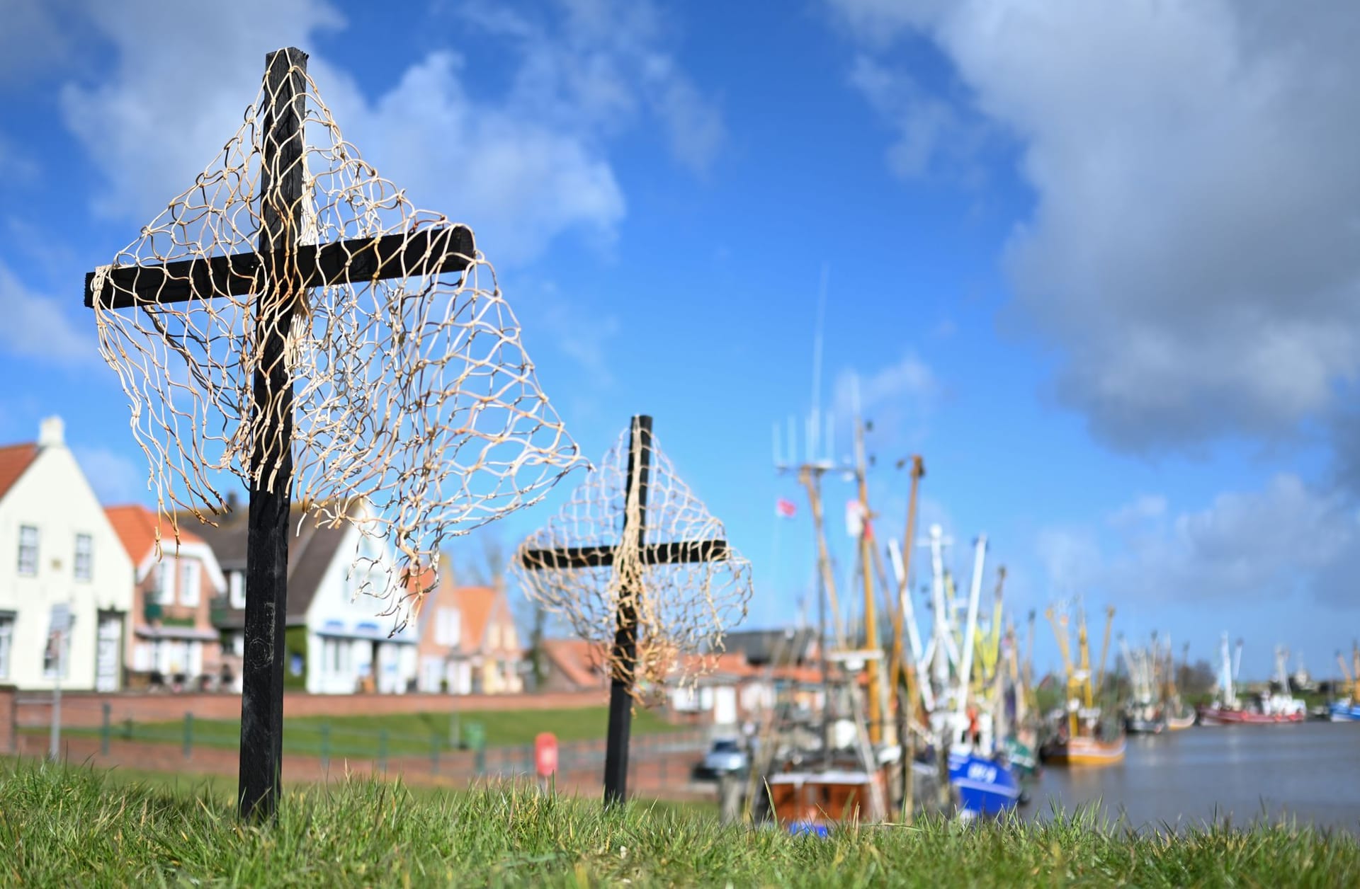 Schwarze Kreuze mit Netzen stehen als stiller Protest der Fischer an einem Hafen: Nordseefischer fürchten um ihre Existenz.