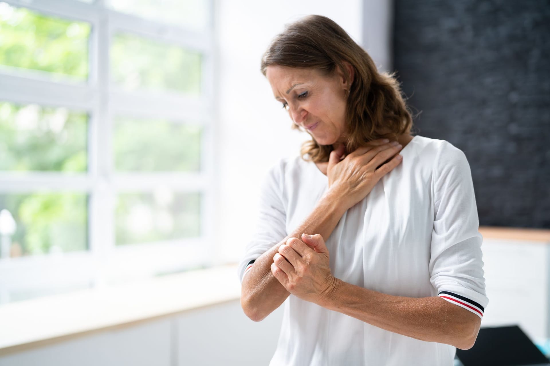 Frau kratzt sich am Arm