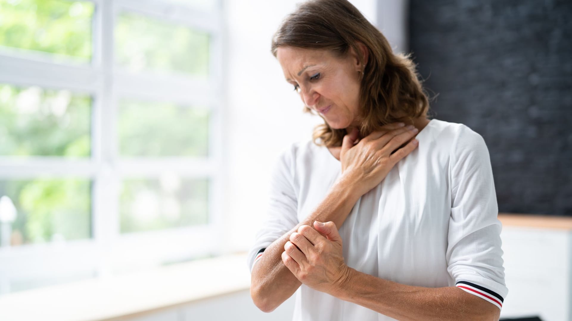 Frau kratzt sich am Arm