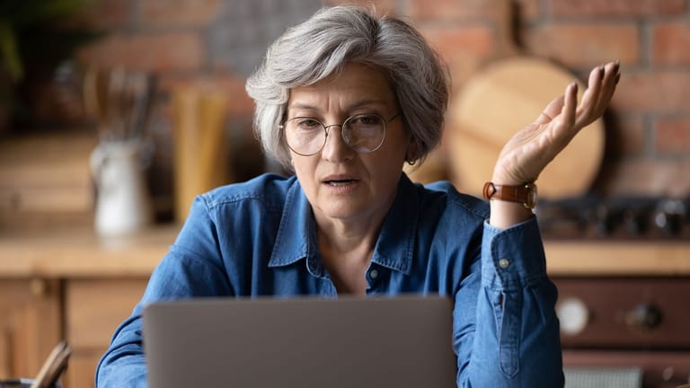 Rentnerin schaut verärgert auf ihr Laptop (Symbolbild): Die Rentenanpassung im Juli führt dazu, dass manche Rentner erstmals Steuern zahlen müssen.