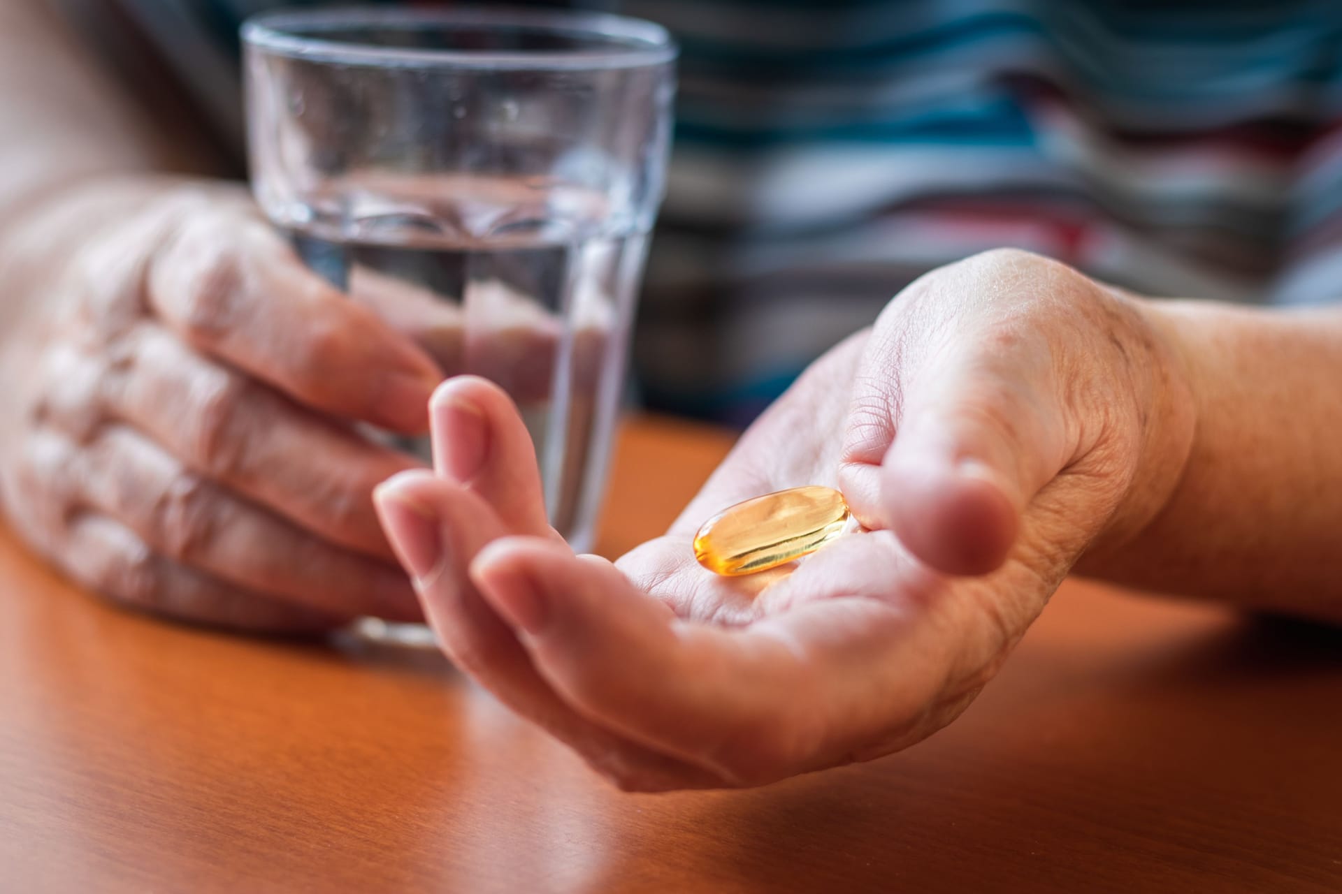 Eine Person nimmt ein Nahrungsergänzungspräparat mit Wasser ein.