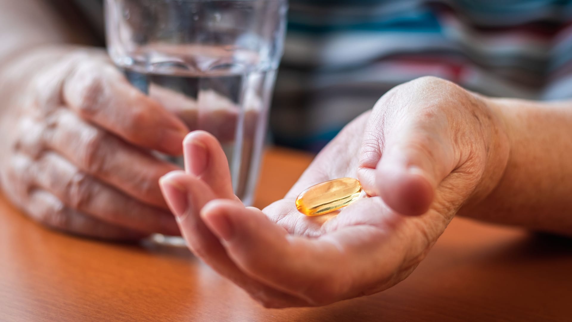 Eine Person nimmt ein Nahrungsergänzungspräparat mit Wasser ein.