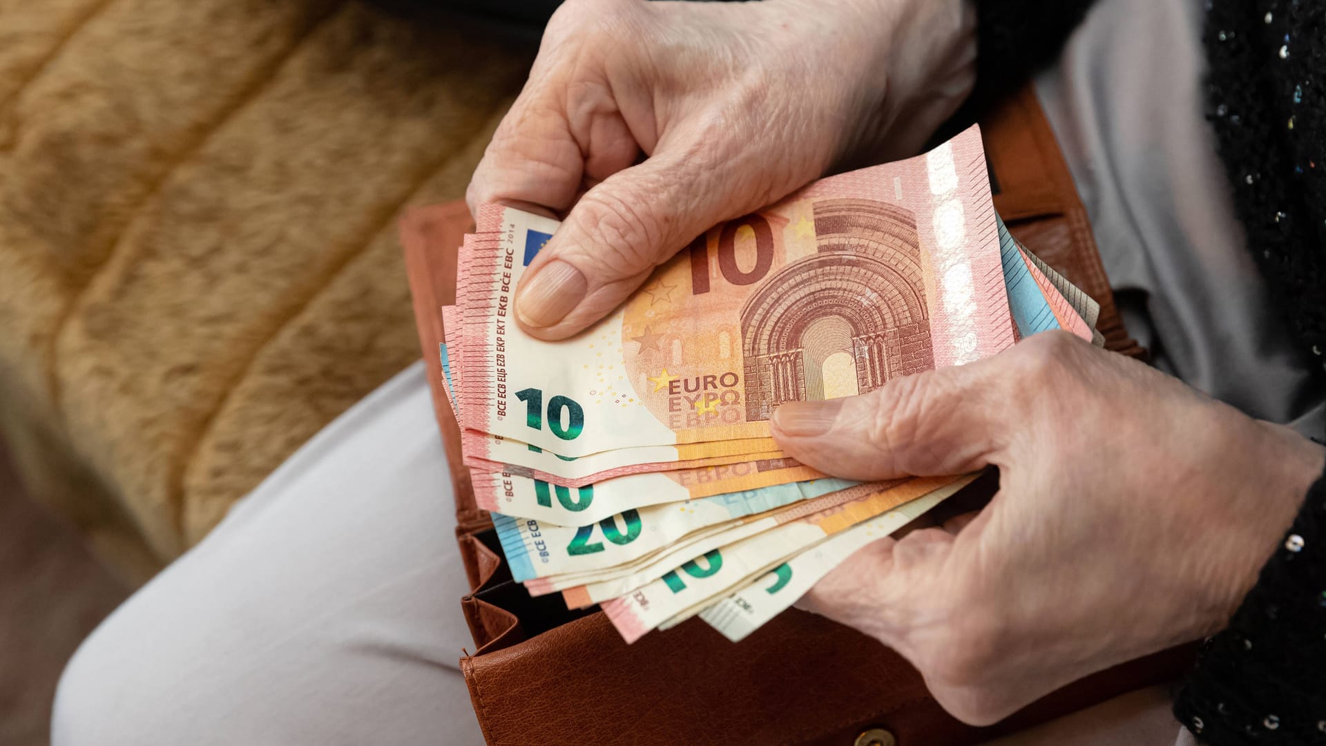 Seniorin hält Geld in der Hand (Symbolbild): Die Rentenerhöhung führt dazu, dass manche Rentner für 2023 eine Steuererklärung machen müssen.