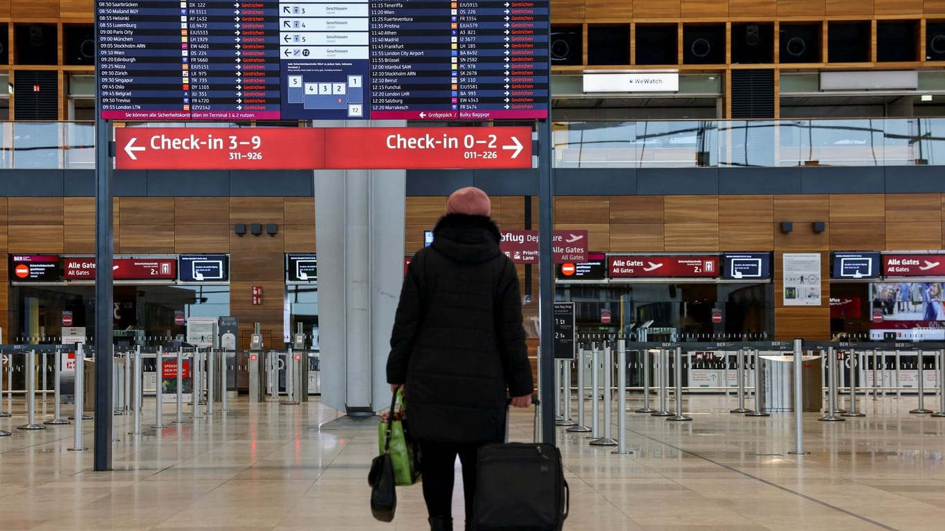 Eine Frau steht vor der Anzeigentafel: Nichts geht mehr am Flughafen BER.