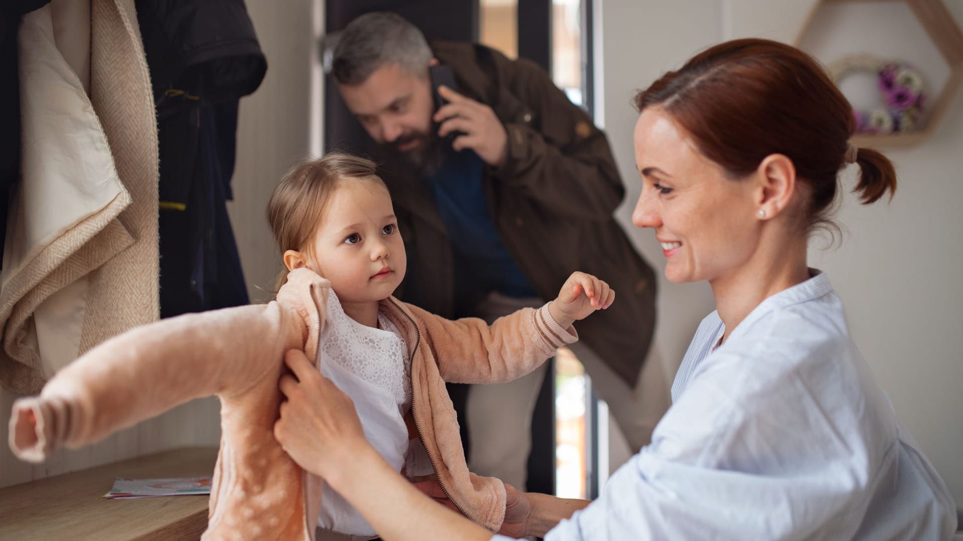 Vater telefoniert auf dem Weg zur Arbeit, Mutter macht die Tochter fertig für die Kita (Symbolbild): Familie und Beruf zu vereinen, ist noch immer eine Herausforderung.