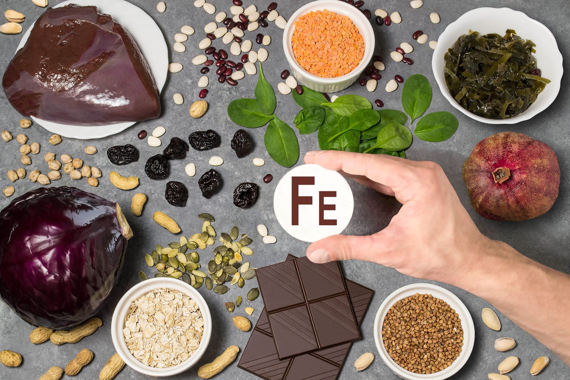 Verschiedene Lebensmittel, in der Mitte eine Hand, die ein Papier mit der Aufschrift "FE" zeigt.