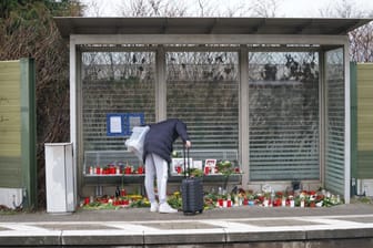 Eine Reisende schaut sich die Blumen, Kerzen und verschiedene Bilder im Wartehäuschen am Bahnhof Brokstedt an: Sie gedenken den Opfern der Messerattacke.