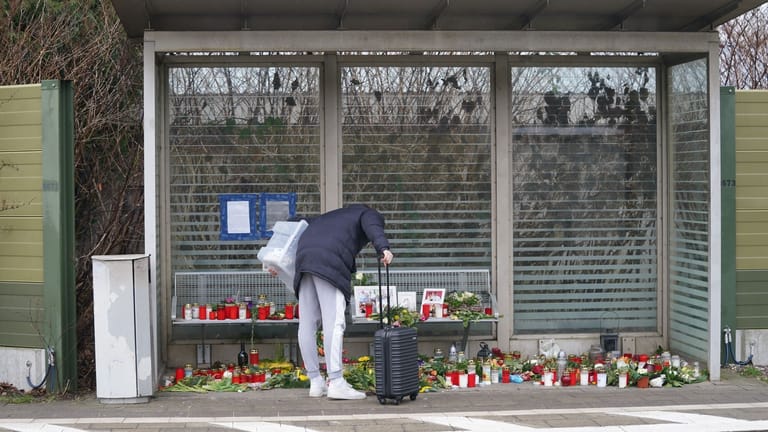 Eine Reisende schaut sich die Blumen, Kerzen und verschiedene Bilder im Wartehäuschen am Bahnhof Brokstedt an: Sie gedenken den Opfern der Messerattacke.