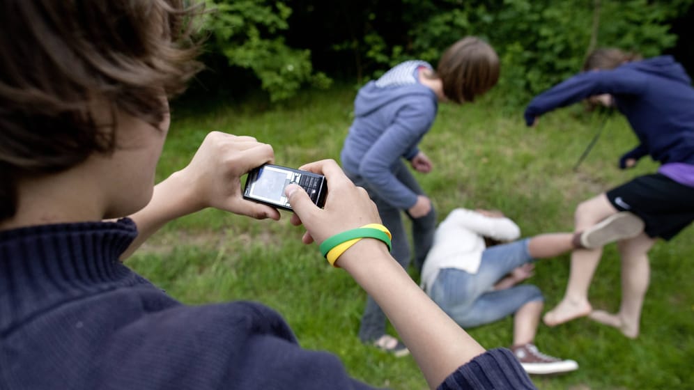 Jugendlicher filmt mit dem Handy, wie ein Mädchen verprügelt wird (Symbolbild): In Heide wurde eine 13-Jährige von anderen Jugendlichen misshandelt.