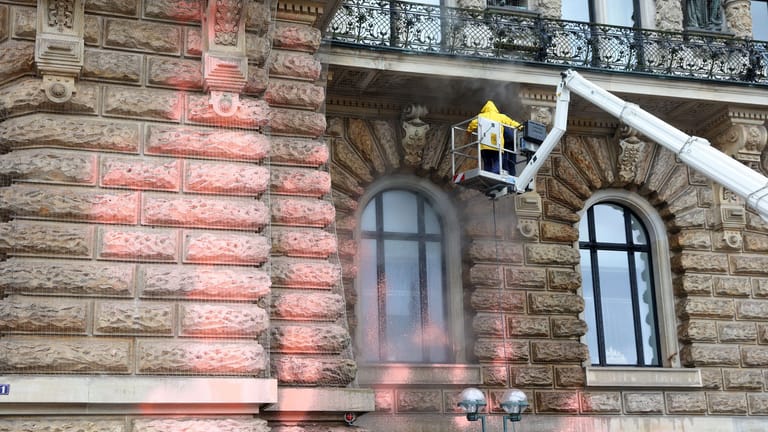Mit einem Dampfstrahler wird die Fassade des Hamburger Rathauses gereinigt: Welche Schäden bei der Farbattacke entstanden sind, wird nun geprüft.