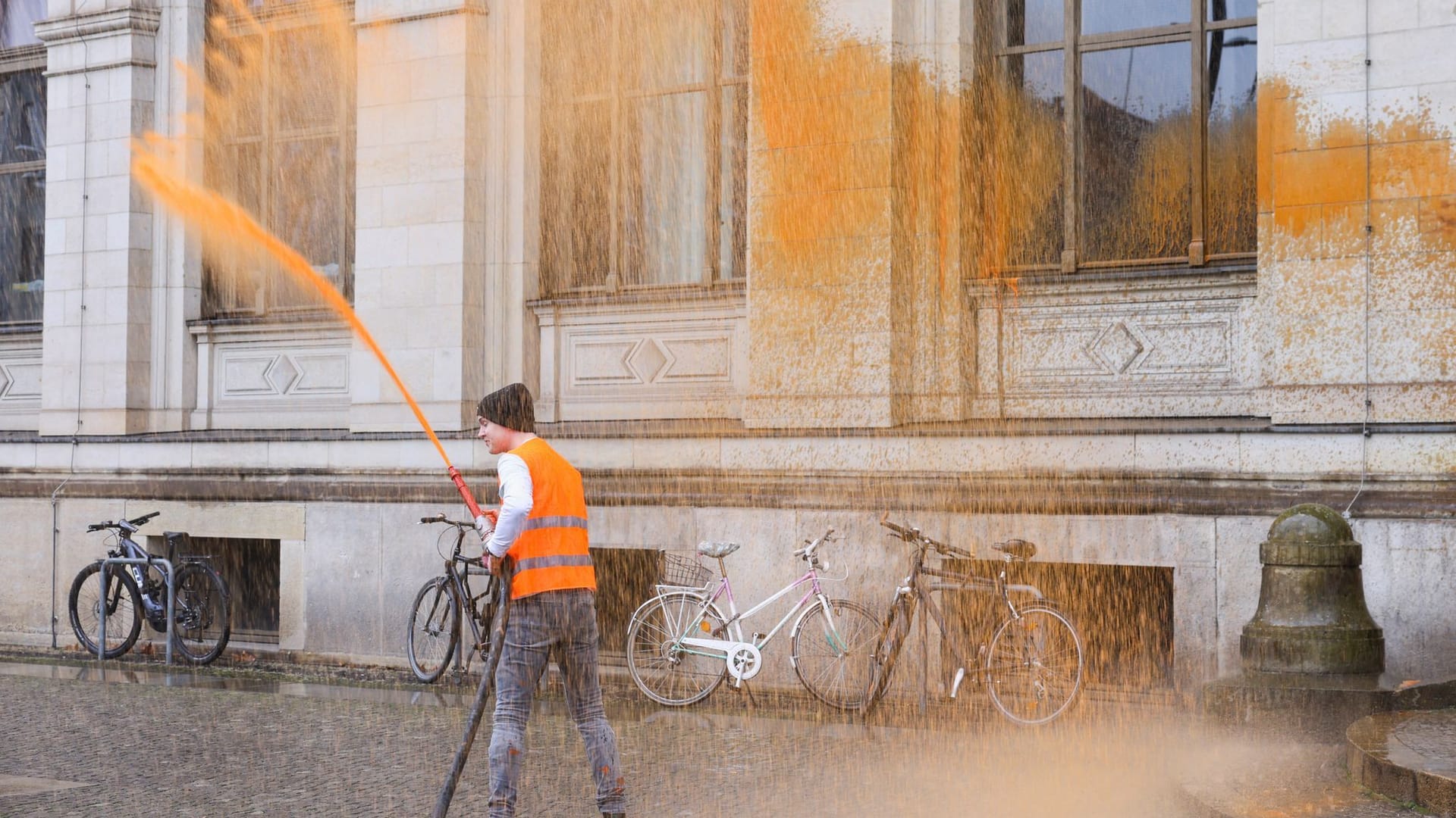 Ein Protestler spritzt mit Farbe: Der Schlauch führt zum vor dem Gebäude geparkten Feuerwehrauto.