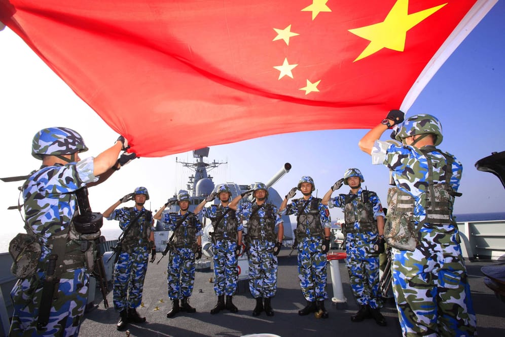 Chinesische Soldaten halten eine Flagge vor einem Zerstörer hoch (Archivbild): Peking will bei den Verteidigungsausgaben kräftig zulegen.