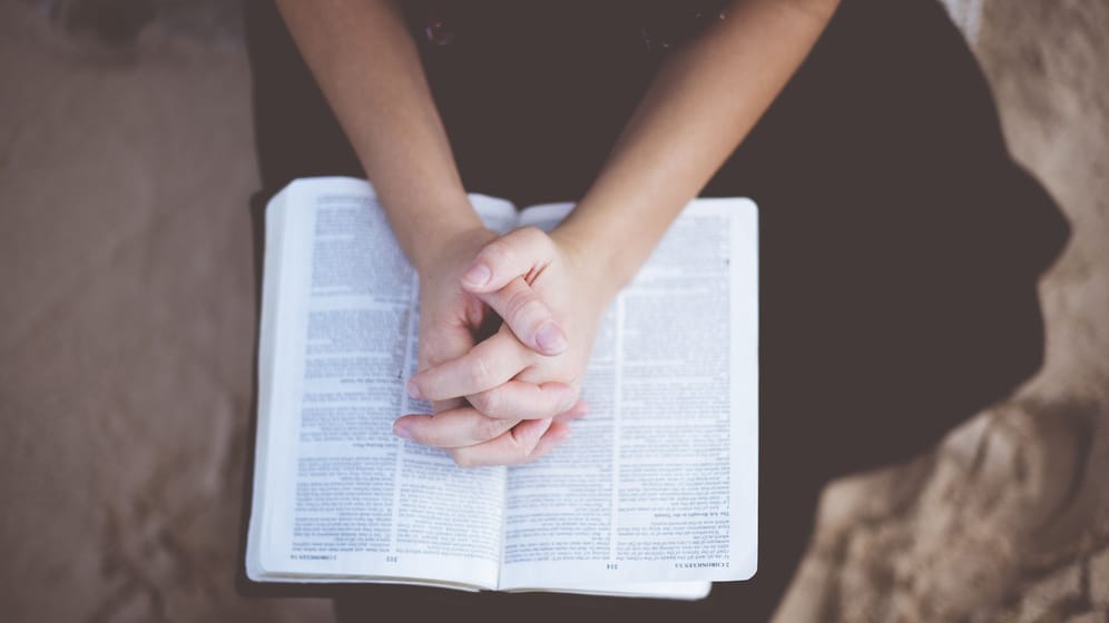 Gefaltete Hände auf einer Bibel (Symbolbild): Die Beziehung eines deutschen Jugendpastors sorgt für Wirbel.
