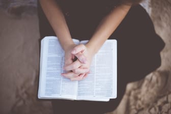 Gefaltete Hände auf einer Bibel (Symbolbild): Die Beziehung eines deutschen Jugendpastors sorgt für Wirbel.