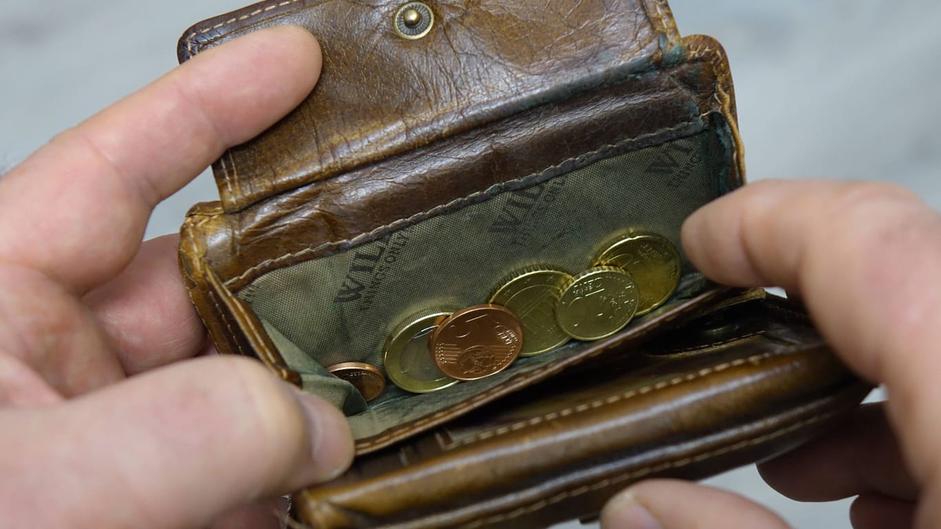 Hände wühlen nach Münzen in einem Portemonnaie (Symbolbild): Die Menschen in Bayern hatten 2022 im Schnitt über drei Prozent weniger Reallohn.