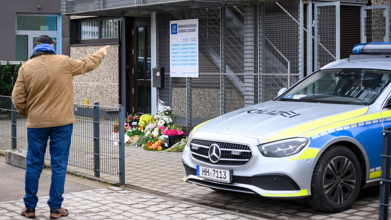 Passanten, Blumen und ein Streifenwagen vor dem Eingangsbereich der Kirche der Zeugen Jehovas Hamburg: Der mutmaßliche Schütze tötete sieben Menschen und anschließend sich selbst.