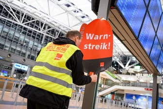 Ein Gewerkschaftsvertreter klebt ein Plakat mit der Aufschrift "Warnstreik!" an die Anzeigetafel im leeren Terminal 2 (Archivbild): Auch am Montag wird am Hamburger Flughafen gestreikt.