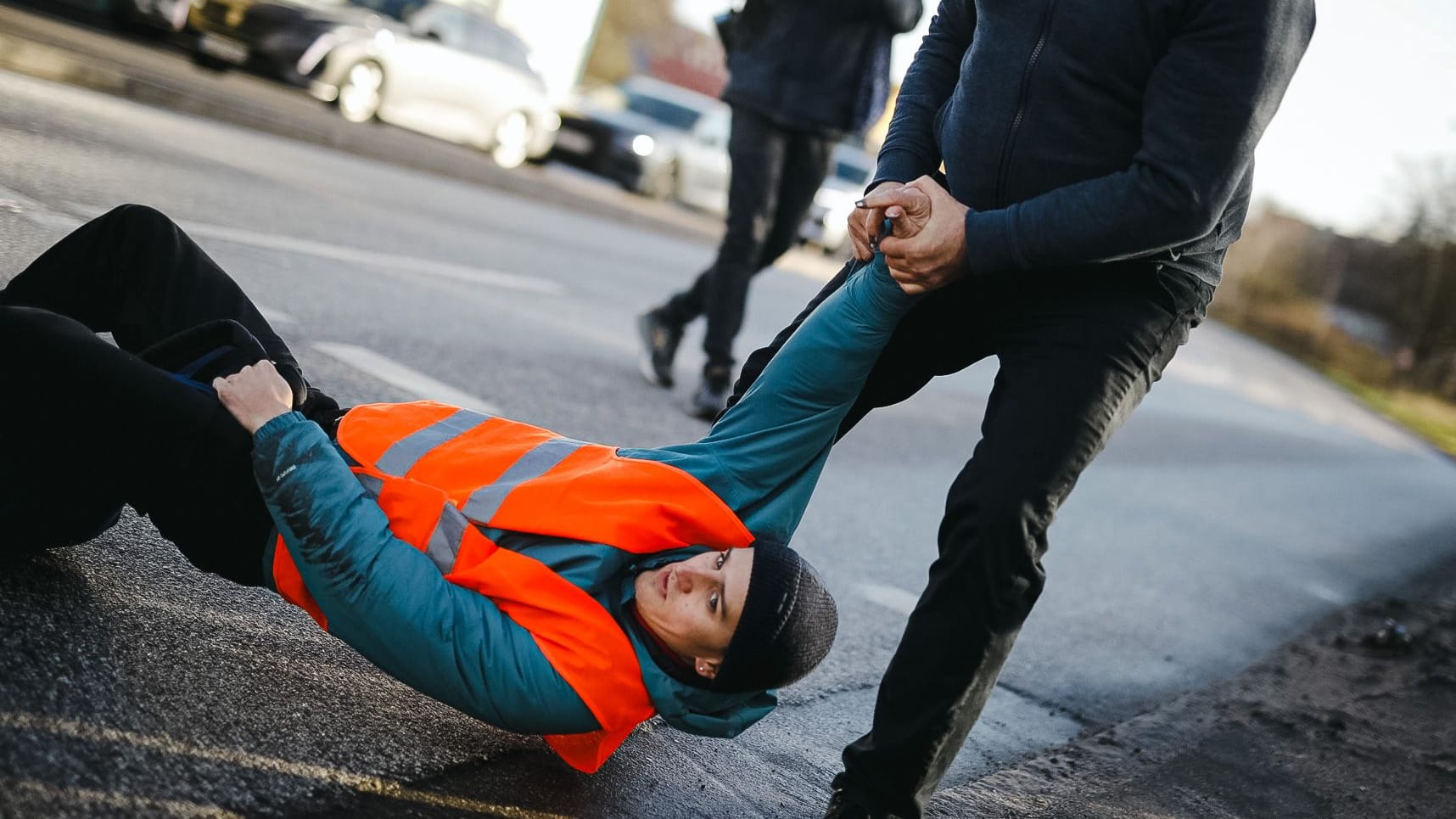 Ein Aktivist wird von der Straße gezogen: Die erneute Blockadeaktion der "Letzten Generation" sorgt für Ärger bei den Verkehrsteilnehmern.