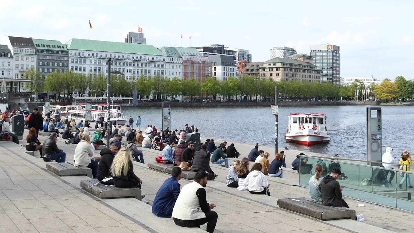 Passanten sitzen bei Frühlingswetter auf den Treppen am Jungfernstieg (Symbolbild): Die Temperaturen in Hamburg sollen endlich steigen.