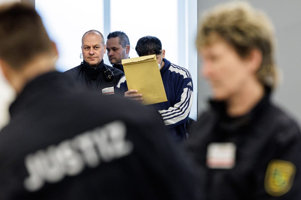 Angeklagte Abdul Majed R. (r) wird von Justizbeamten in Handschellen in den Gerichtssaal des Oberlandesgerichts Dresden geführt. Seit Ende Januar wird gegen insgesamt sechs junge Männer wegen schweren Bandendiebstahls, Brandstiftung und besonders schwerer Brandstiftung verhandelt.