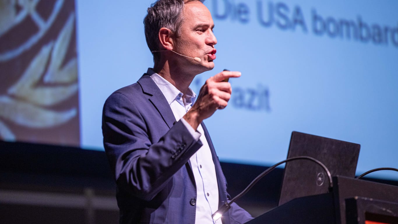 Daniele Ganser bei einem Vortrag 2019 in Karlsruhe: Auf der Leinwand im Hintergrund wird sein Lieblingsthema behandelt: die USA.