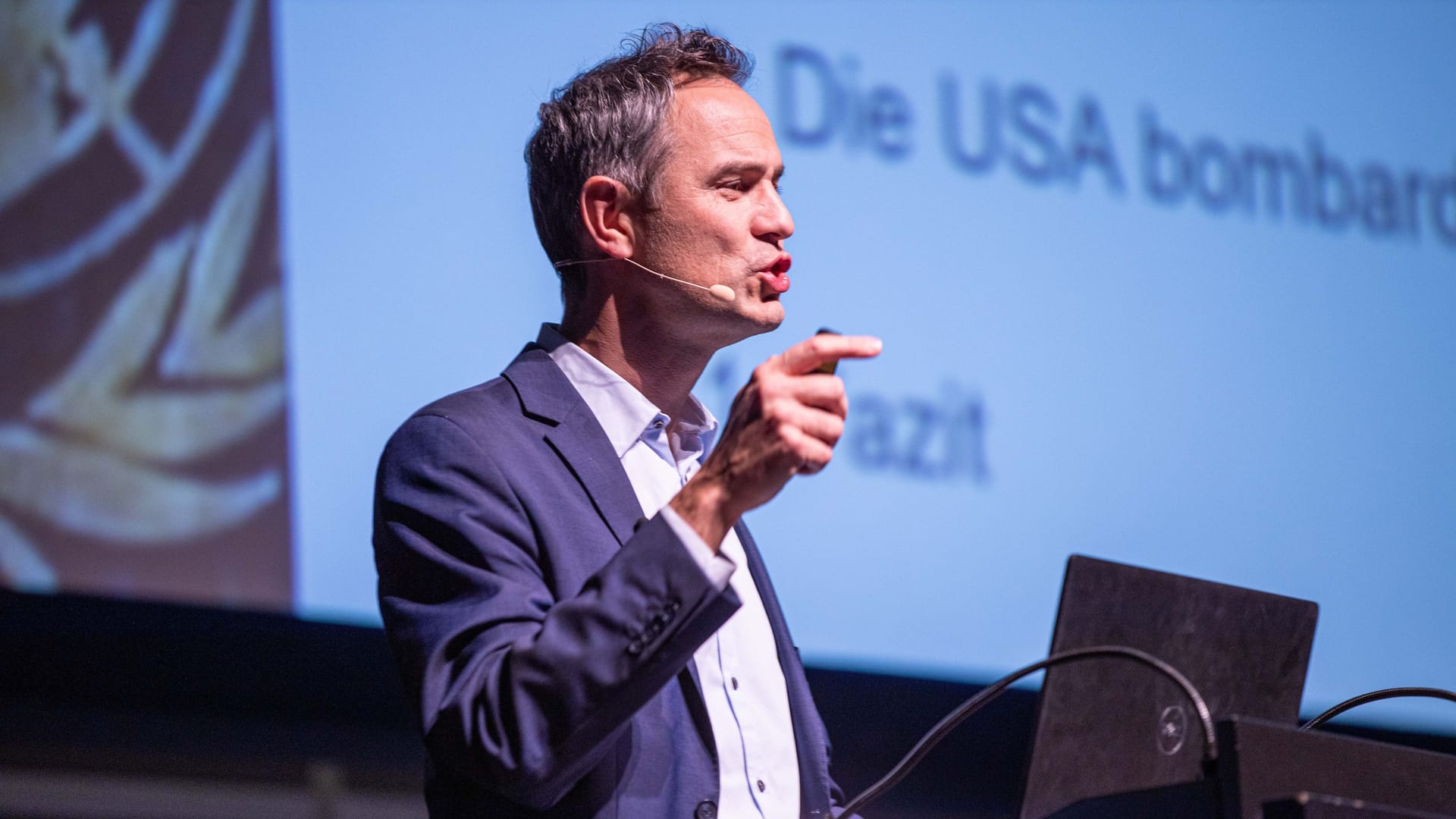 Daniele Ganser bei einem Vortrag 2019 in Karlsruhe: Auf der Leinwand im Hintergrund wird sein Lieblingsthema behandelt: die USA.