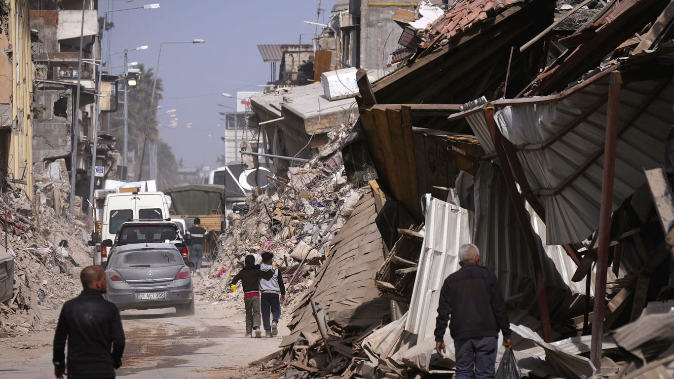 Anwohner gehen auf einer Straße in Antakya an den Trümmern von Gebäuden vorbei: Durch das Erdbeben vom 6. Februar wurden ganze Straßenzüge und Stadtteile beschädigt.