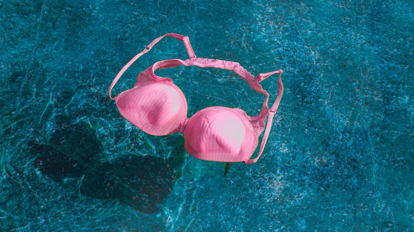 Bikini-Oberteil schwimmt im Becken eines Hallenbads.