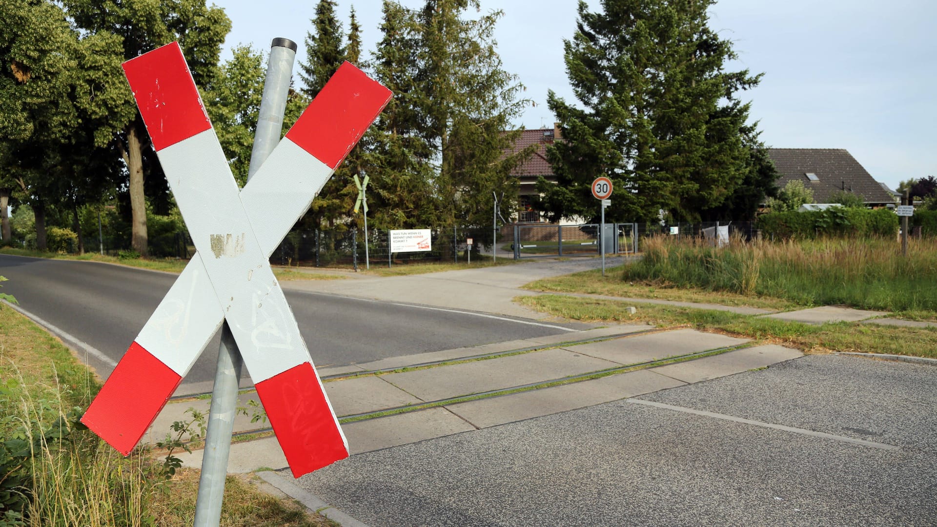 Andreaskreuz: Das Zeichen und eine dicke weiße Linie sind direkt am Bahnübergang angebracht. Es räumt dem Schienenverkehr Vorrang vor dem Straßenverkehr ein. Denn weil Stahl auf glatten Stahlschienen reibt, hat der obendrein schwere Zug einen sehr langen Bremsweg.