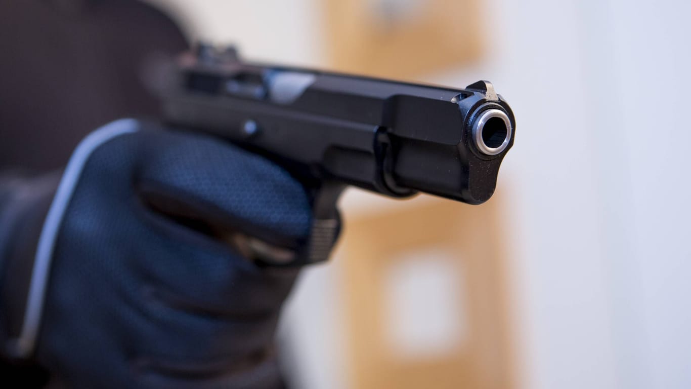 Ein Mann zielt mit einer Schusswaffe (Symbolbild): Ein Zeitungsausträger wurde schwer verletzt.