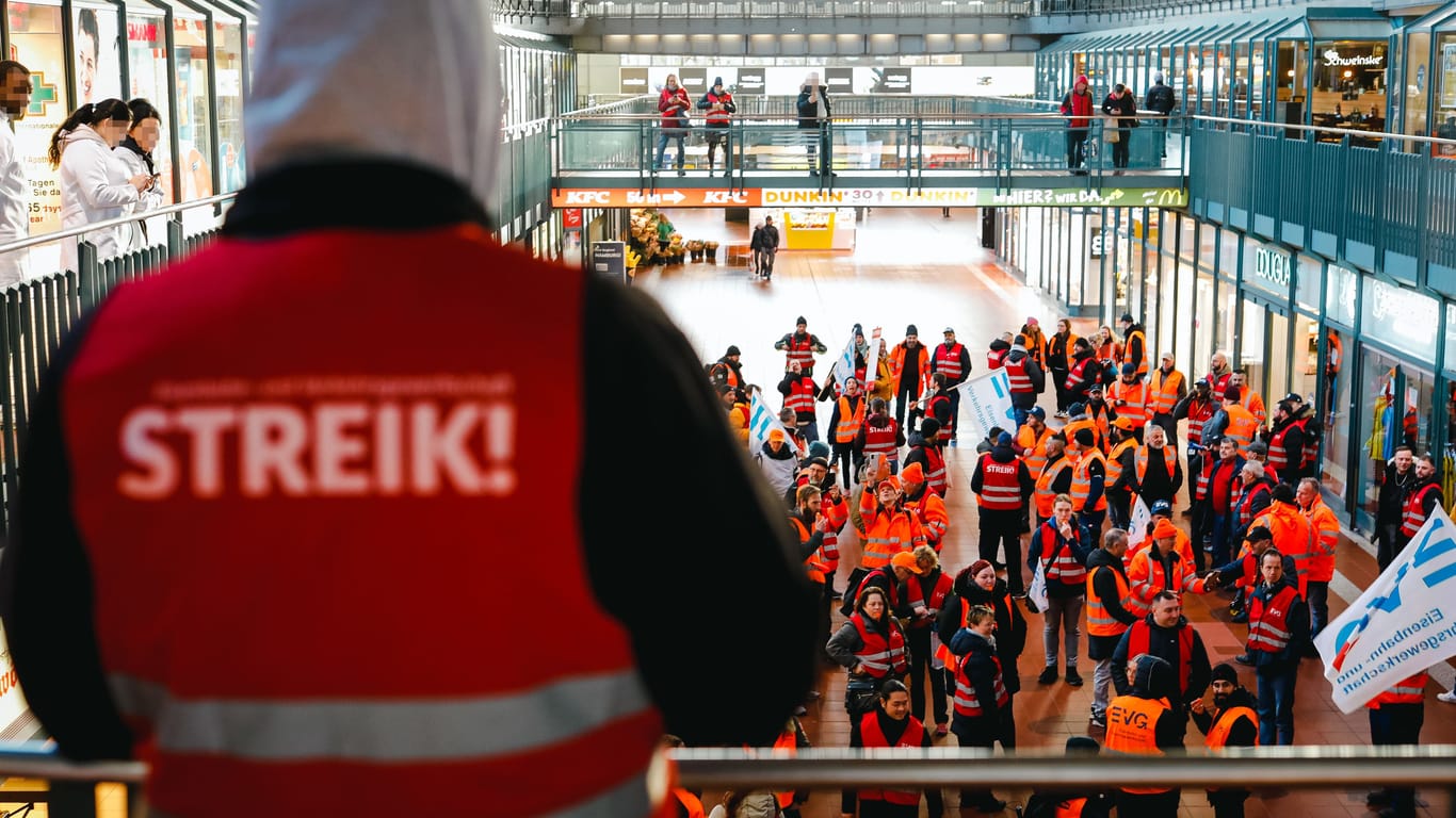 "Streik" steht auf der orangen Warnweste eines Streikenden: Mit Trillerpfeifen ziehen sie am Montagmorgen durch den Hamburger Hauptbahnhof.
