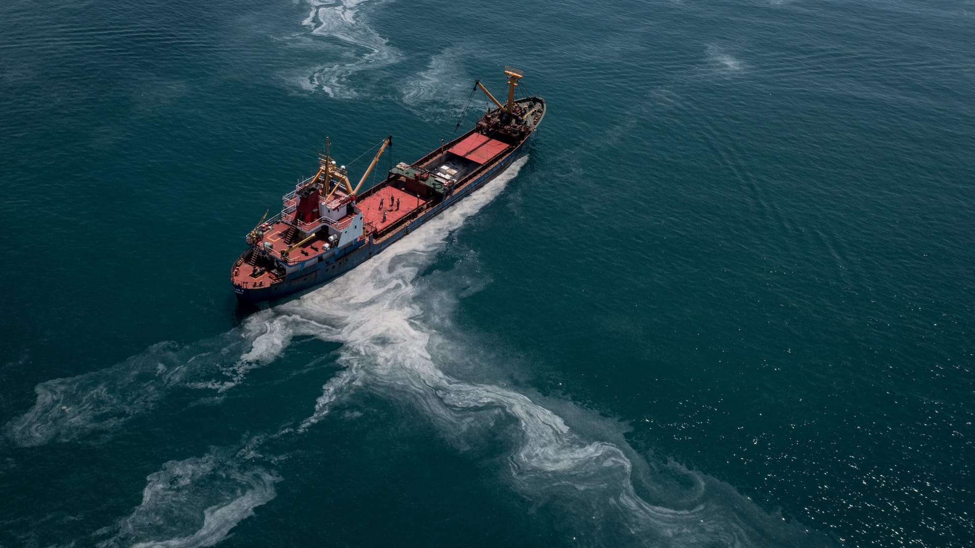 Ein Frachtschiff fährt übers Meer: Das Wasser der Ozeane erscheint immer grüner.