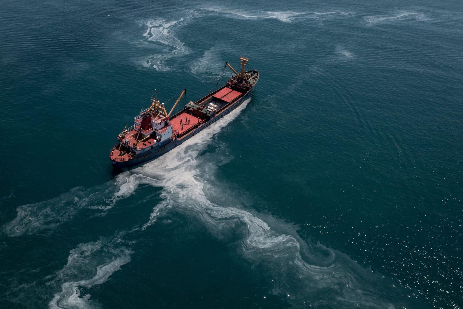 Ein Frachtschiff fährt übers Meer: Das Wasser der Ozeane erscheint immer grüner.