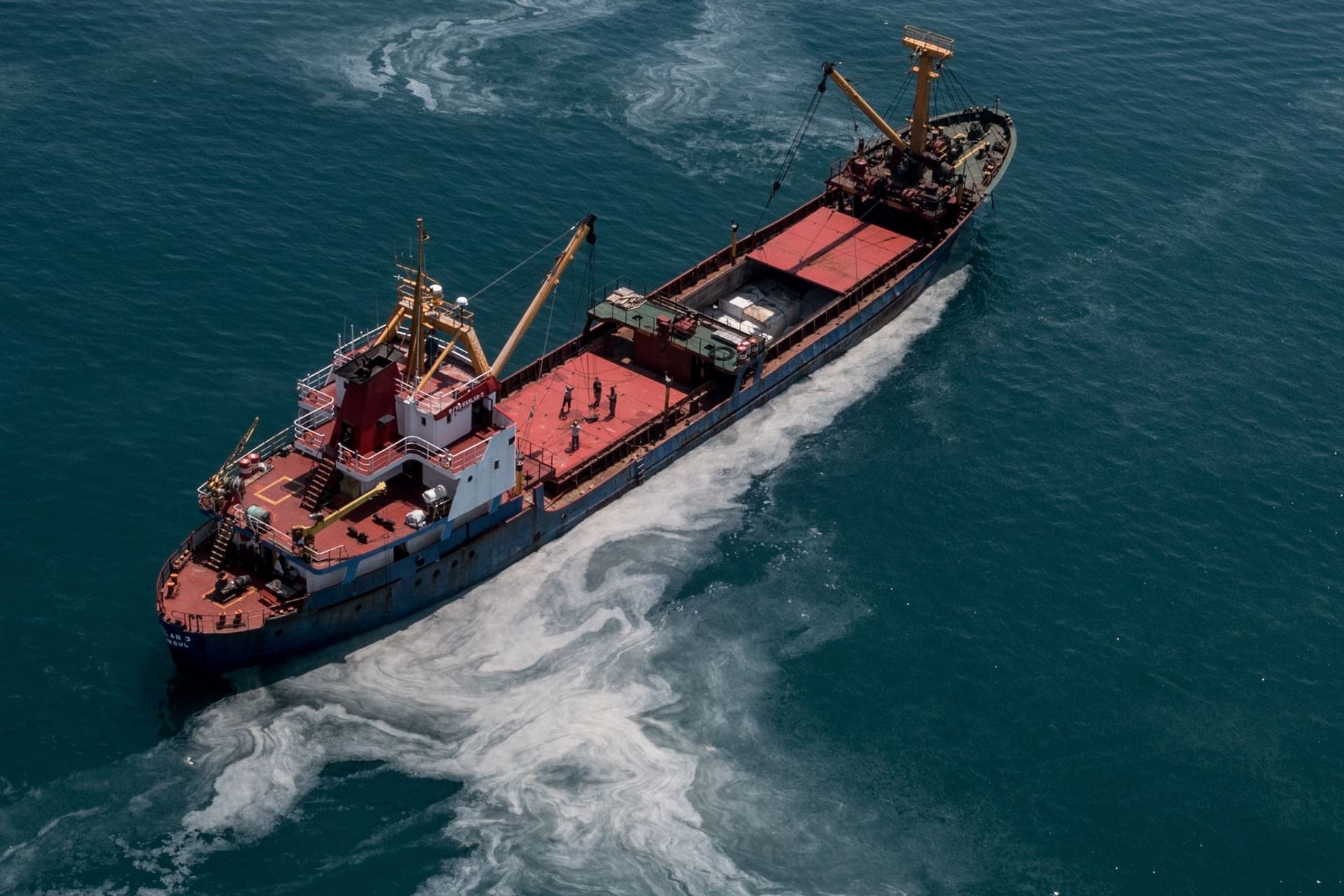 Ein Frachtschiff fährt übers Meer: Das Wasser der Ozeane erscheint immer grüner.