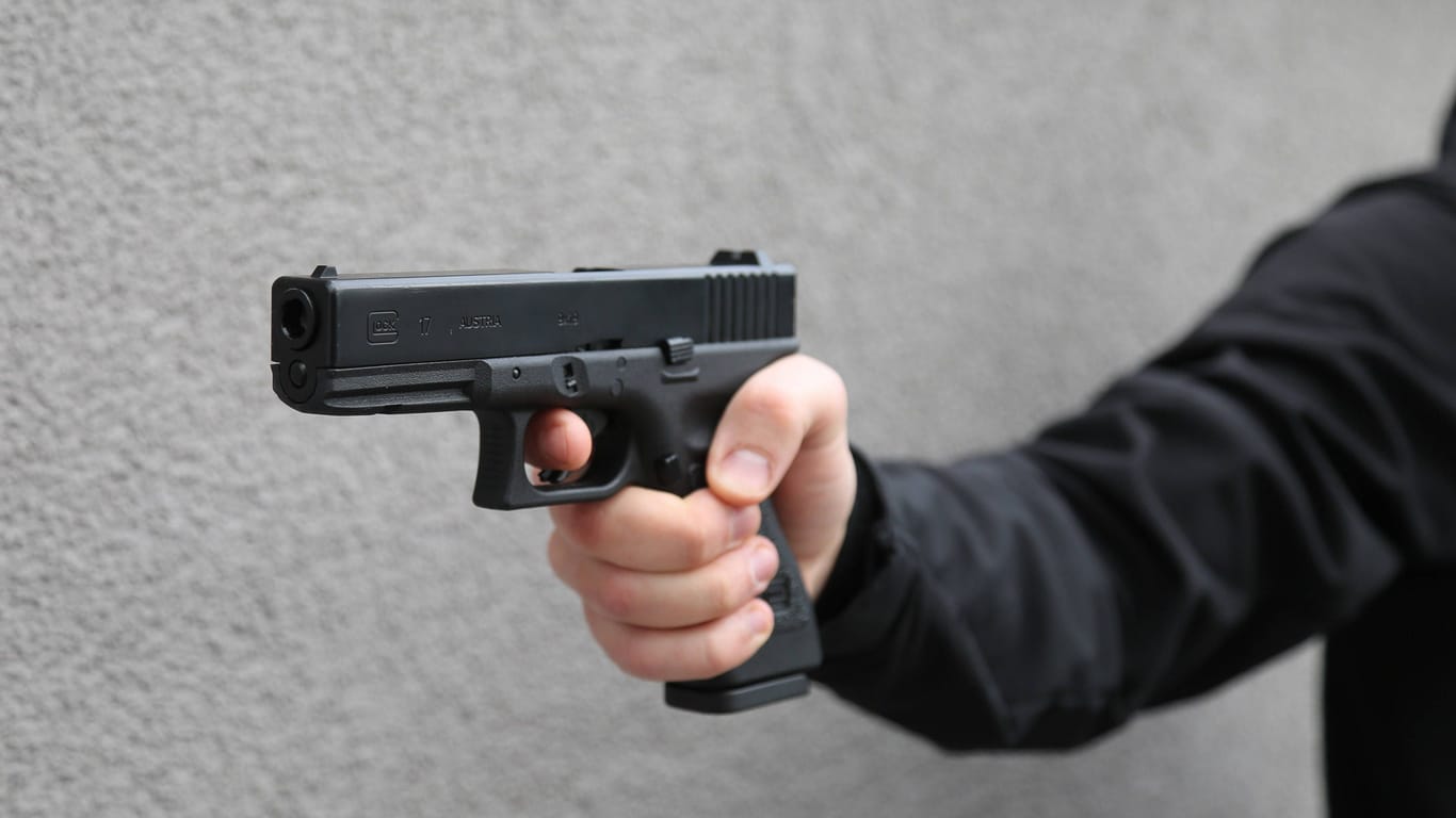 Ein Mann hält eine Pistole (Archivbild): In Berlin hat eine Person auf seine eigene Familie geschossen.