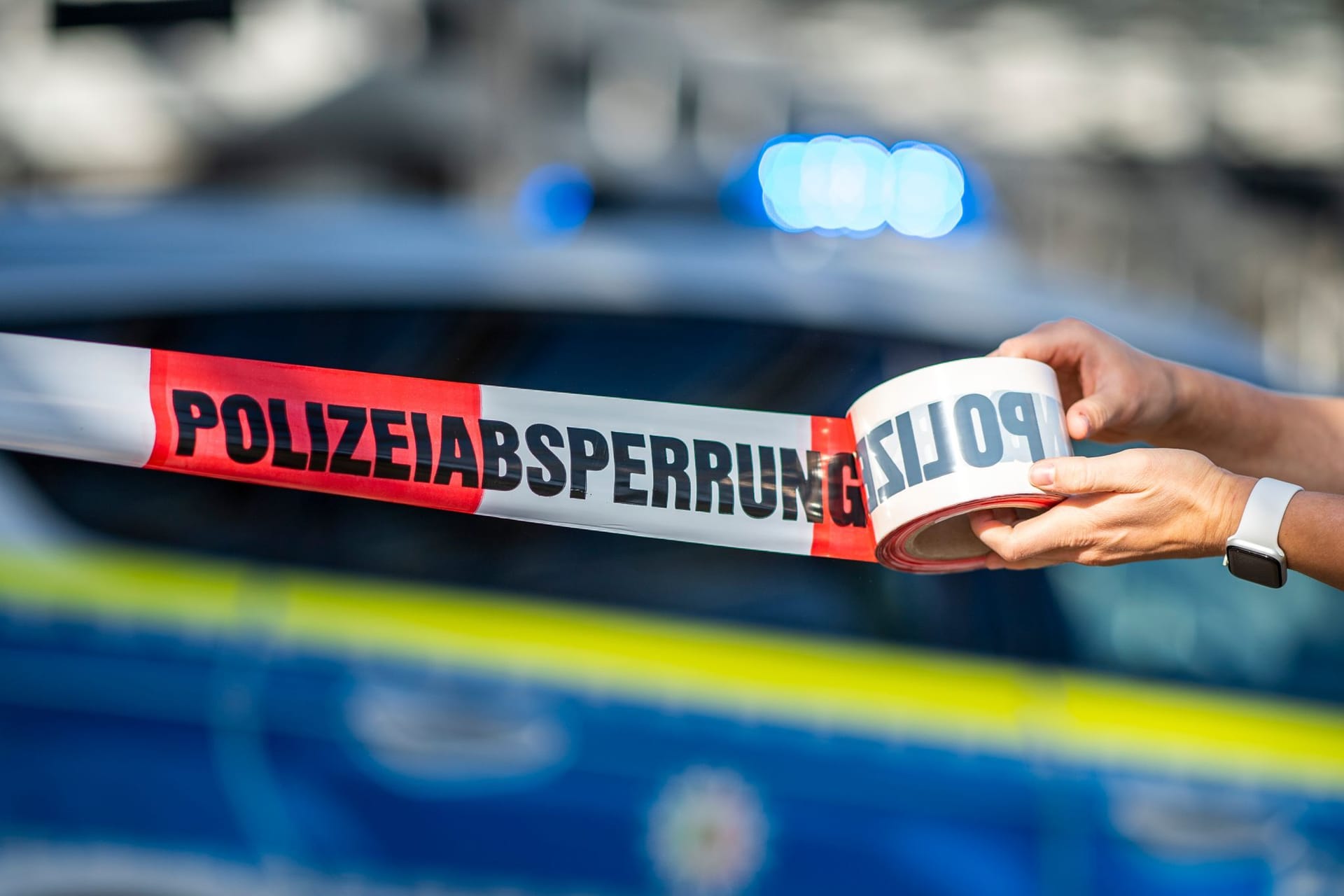 Ein Absperrband wird vor einem Polizeiwagen ausgerollt: In Hamburg wurde die Überreste eines Toten gefunden.