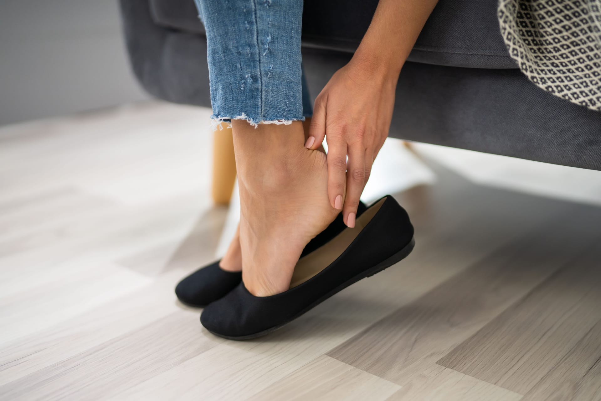 Eine Frau fasst sich an die schmerzende Ferse: Eine Plantarfasziitis lässt sich auch mit Hausmitteln lindern.