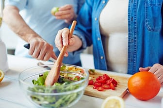 Mann und Frau höheren Alters bereiten Salat zu
