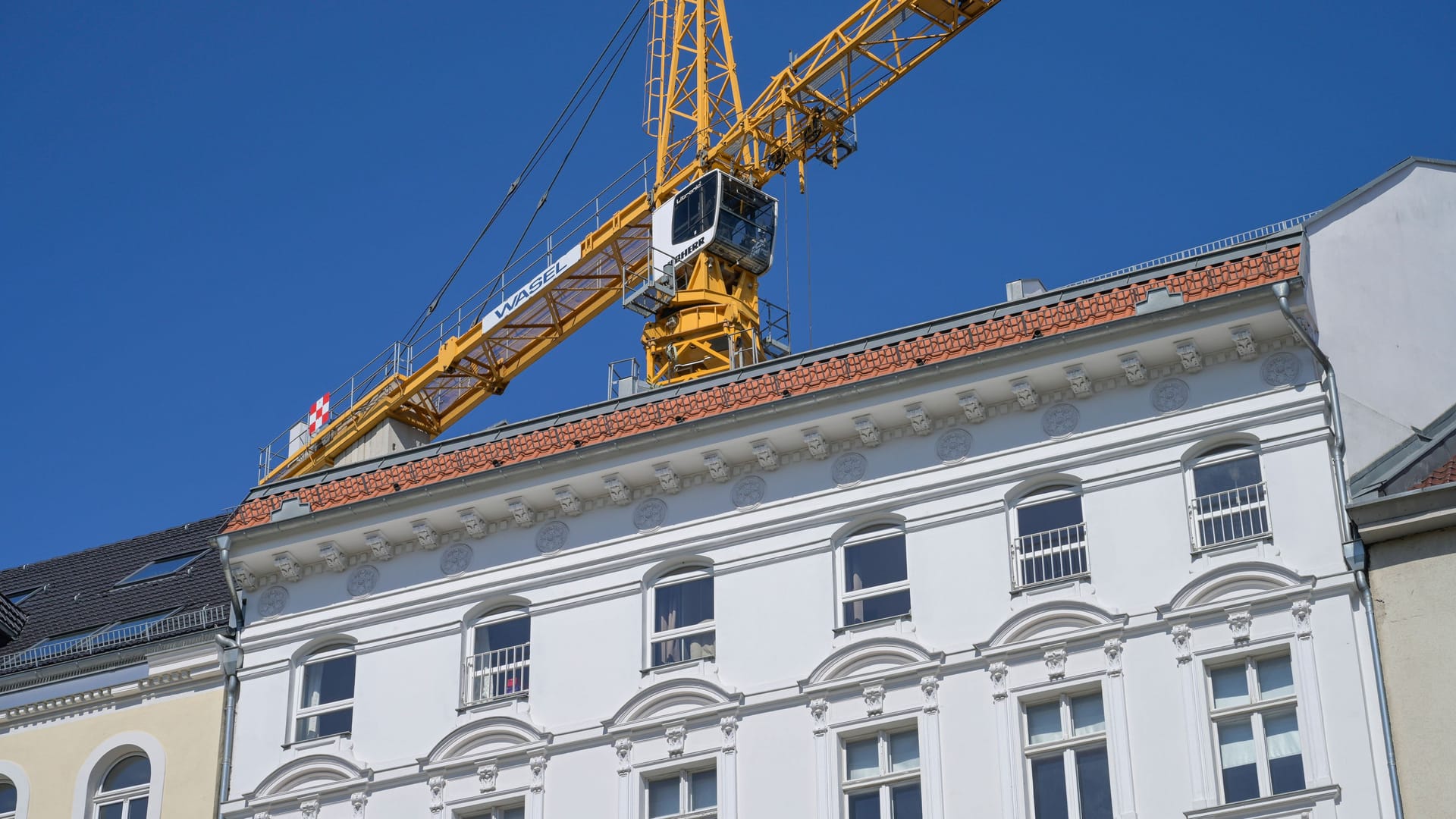 Kran über einem Altbau: Viele Bauprojekte werden derzeit auf Eis gelegt.