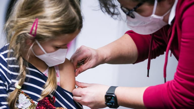 Eine Ärztin klebt einem Kind nach der Impfung ein Pflaster auf: Kinder leiden seltener an schweren Verläufen einer Coronainfektion.