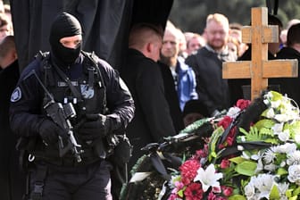 Schwer bewaffnete Sicherheitsleute sind auf einem Friedhof in St. Petersburg im Einsatz, wo der militante Blogger Maxim Fomin beerdigt wurde.