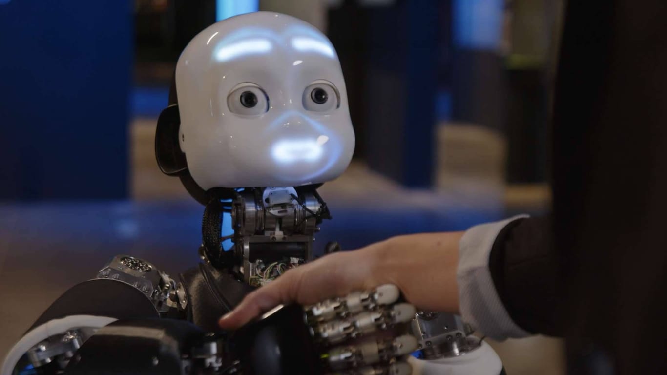 iCub3: Ein humanoider Roboter gibt einem Mensch die Hand. (Symbolbild)