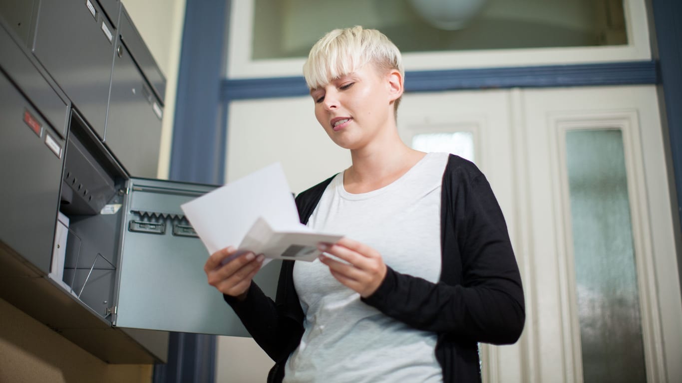 Eine Frau öffnet einen Brief (Symbolbild): Post vom Vermieter ist meist kein gutes Zeichen.